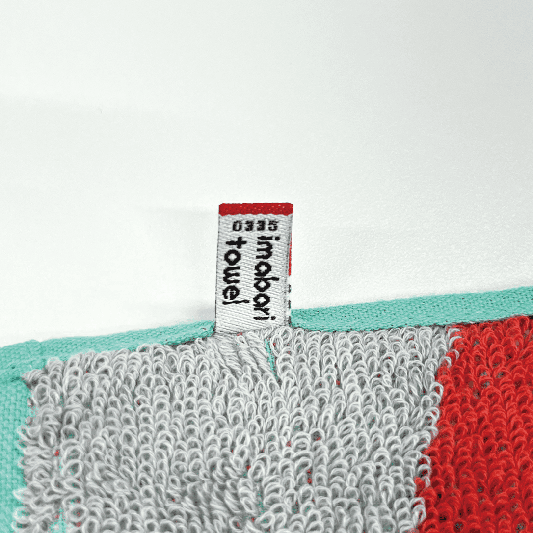 高品質の証、今治タオルブランド認定マークとネームタグを縫い付ける『製造工程』。